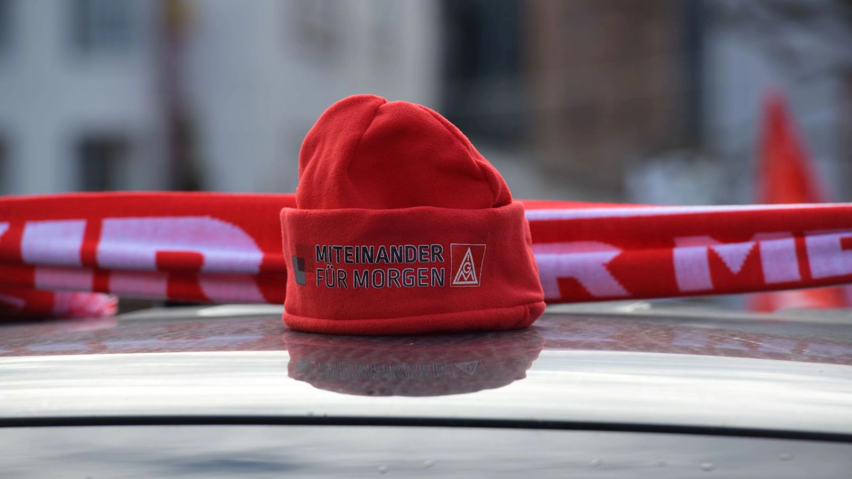 Rote IG Metall-Mütze mit Schriftzug "Miteinander für morgen" auf Autodach
